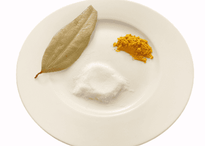 bay leaf, salt, and turmeric on a white plate